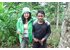 The photo shows two people holding freshly harvested ginger and galangal in their hands.