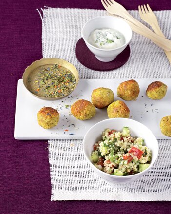 Auf dem Foto ist ein weißes Tablett mit Falafeln darauf zu sehen. Daneben steht eine Schüssel mit Tabouleh und ein Schüsselchen mit Dip. | © SONNENTOR