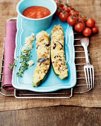 Auf dem Foto sind zwei Zucchini Hälften gefüllt mit Pilzen und Couscous zu sehen. Daneben sieht man auch Tomaten und Salsa Sauce. | © SONNENTOR