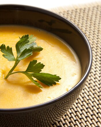 Auf dem Foto ist eine schwarze Schale mit Kürbiscremesuppe zu sehen. Darauf ist Petersilie zu sehen. | © SONNENTOR