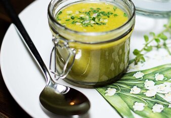 Auf dem Foto sieht man ein Glas mit veganer Gemüsesuppe. Das Einmachglas steht auf einem weißen Teller mit frühlingshafter Serviette. | © SONNENTOR