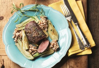 Auf dem Foto sieht man ein Teller mit einem Lammfilet auf Fenchel und Orangensauce. Dahinter sieht man eine Sauce und daneben liegt das Besteck. | © SONNENTOR