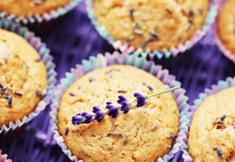 Auf dem Foto sind Muffins zu sehen. Darauf ist zarter Lavendel zu sehen. Auf einem Muffin liegt ein ganzer Lavendelzweig. | © SONNENTOR