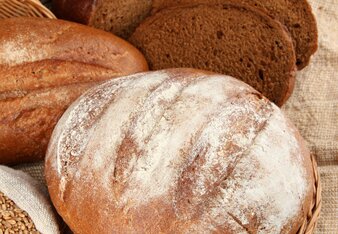 Auf dem Foto sieht man ein Laib Sauerteigbrot. Daneben sieht man ein aufgeschnittenes Brot. | © SONNENTOR