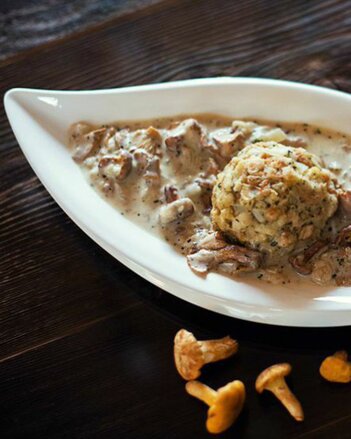 Auf dem Foto ist eine Schale mit Eierschwammerlsauce zu sehen. Darin liegt auch eine Knödel. Neben der Schale sind frische Eierschwammerl zu sehen. | © SONNENTOR