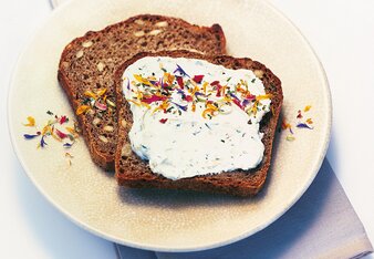 Auf dem Foto ist Brot mit dem Gute Laune Kräutertopfen zu sehen. Darüber gestreut ist das bunte Gute Laune Gewürz. | © SONNENTOR