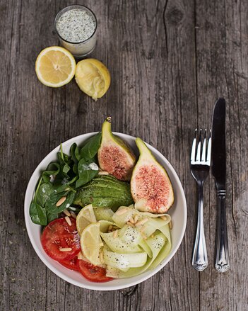 Auf dem Foto ist eine Bowl mit Feigen, Spinat, Tomaten und weiterem Gemüse zu sehen. Daneben sind Zitronen und ein Dip zu sehen. | © SONNENTOR