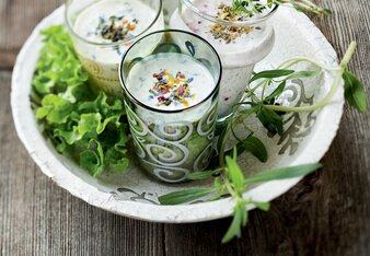 Auf dem Foto sind drei Gläser mit dem Gute Laune Joghurt Dressing zu sehen. Neben den Gläsern sind auch Salat und Kräuter zu sehen. | © SONNENTOR