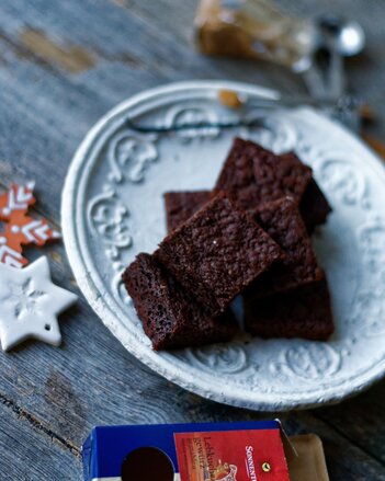 Auf dem Foto ist ein weißer Teller mit Lebkuchen Brownies zu sehen. Davor liegt eine Packung SONNENTOR Lebkuchengewürz. | © SONNENTOR