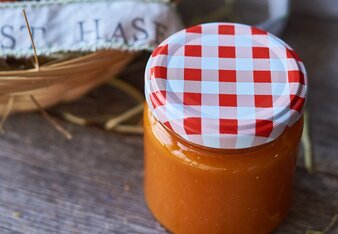 Auf dem Foto sieht man ein Glas mit der orangenen Osterhasen Marmelade. Daneben steht ein Körbchen mit noch einem Glas darin. | © SONNENTOR