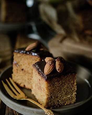 Auf dem Foto sind zwei Stück Weihnachtlicher Gewürzkuchen zu sehen. Er hat eine Schokoglasur und darauf sind Mandeln zu sehen. | © SONNENTOR