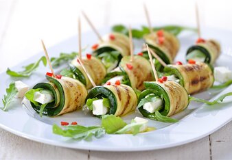 Auf dem Foto sind Schafkäse Zucchiniröllchen zu sehen. Darauf verteilt liegt Rucola. | © SONNENTOR