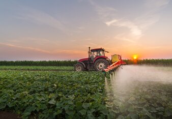 Foto von einem Traktor, der übers Feld fährt und Ackergifte spritzt. | © SONNENTOR