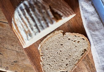 Auf dem Foto sieht man das Roggen-Sauerteigbrot. Daneben liegt eine davon abgeschnittene Scheibe. | © SONNENTOR