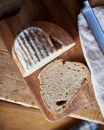 Auf dem Foto sieht man das Roggen-Sauerteigbrot. Daneben liegt eine davon abgeschnittene Scheibe. | © SONNENTOR