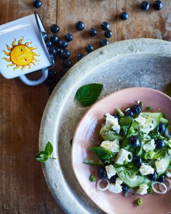 Auf dem Foto ist ein Teller voll mit Salat zu sehen. Dahinter liegen Heidelbeeren. | © SONNENTOR