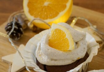 Auf dem Foto ist ein Cupcake zu sehen, der mit einer Creme und Orange verfeinert ist. Daneben sind Zapfen zu sehen. | © SONNENTOR