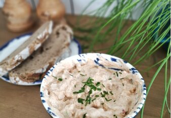 Auf dem Foto sieht man eine Schale mit klassischem Liptauer. Dahinter sieht man zwei Scheiben Brot und zwei Gewürzmühlen. | © SONNENTOR