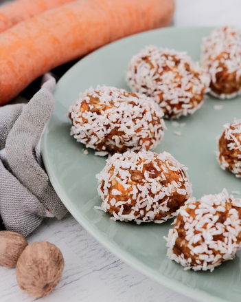 Auf dem Foto sind mehrere Energy-Balls zu sehen. Daneben sieht man Karotten. | © SONNENTOR