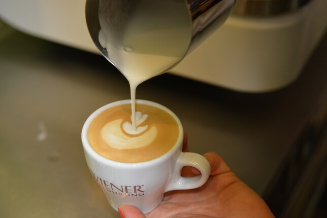 Auf dem Foto ist zu sehen, wie jemand mit Milchschaum Herzen in den Kaffee gießt. | © SONNENTOR