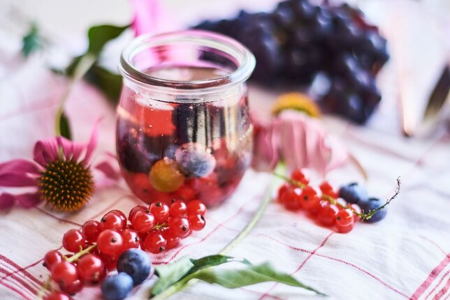 Auf dem Foto sieht man eine Cocktail Bowle. Daneben sind Heidelbeeren und Ribisel zu sehen. | © SONNENTOR