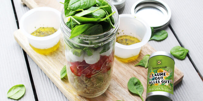 Auf dem Foto sieht man ein Glas gefüllt mit Caprese-Salat. Daneben liegt eine SONNENTOR Gewürzdose Laune gut, alles gut. | © SONNENTOR