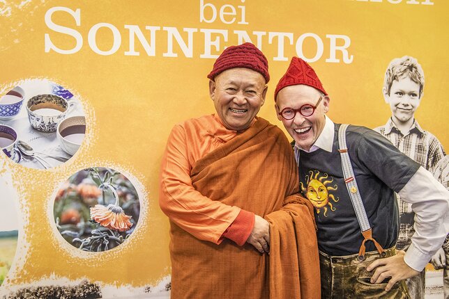 Auf dem Foto sieht man Kyabgögn Chetsang mit Johannes Gutmann vor einer Sonnentor Tafel. | © SONNENTOR